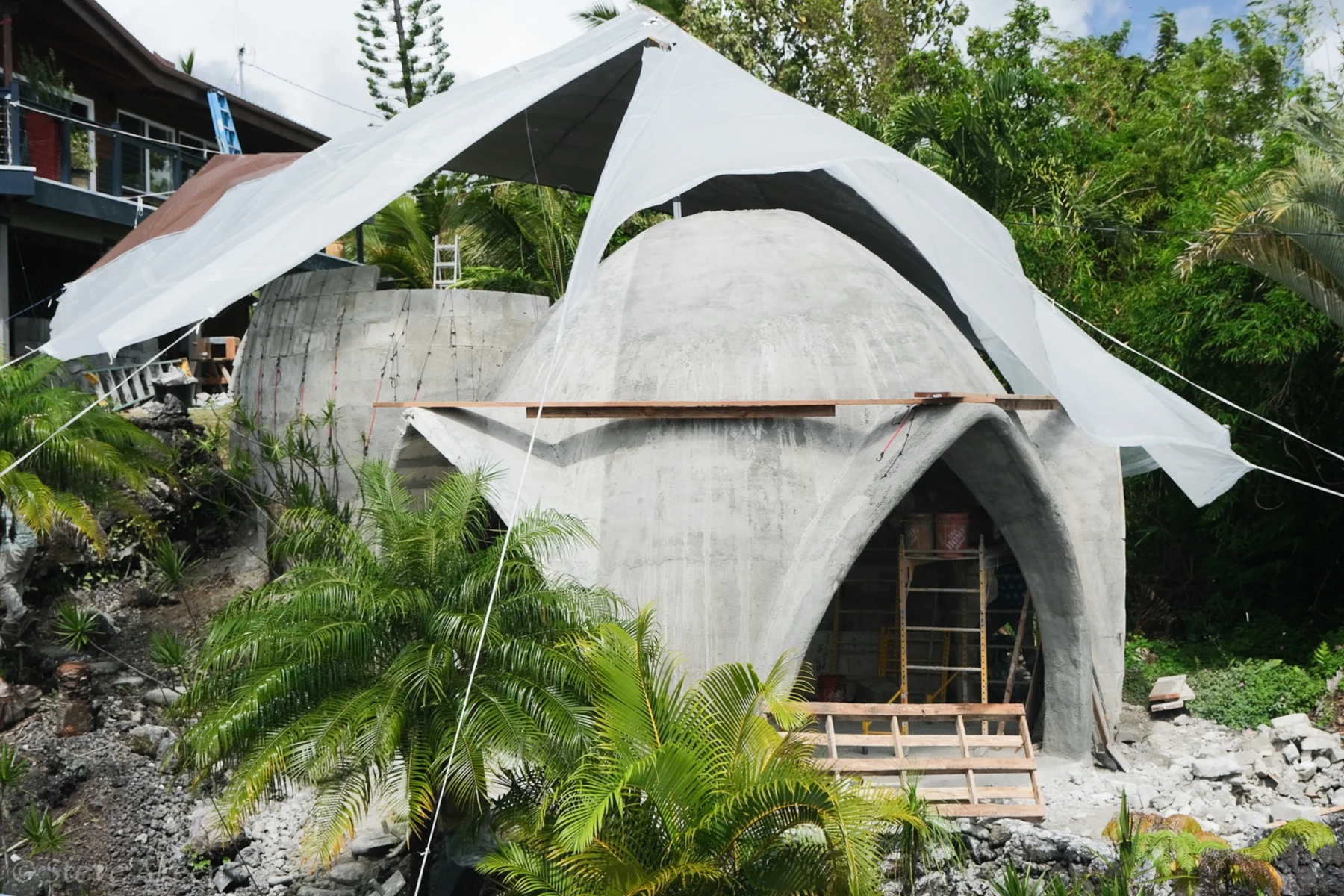 Hawaii Dome aircrete dome under construction in a tropical landscape.