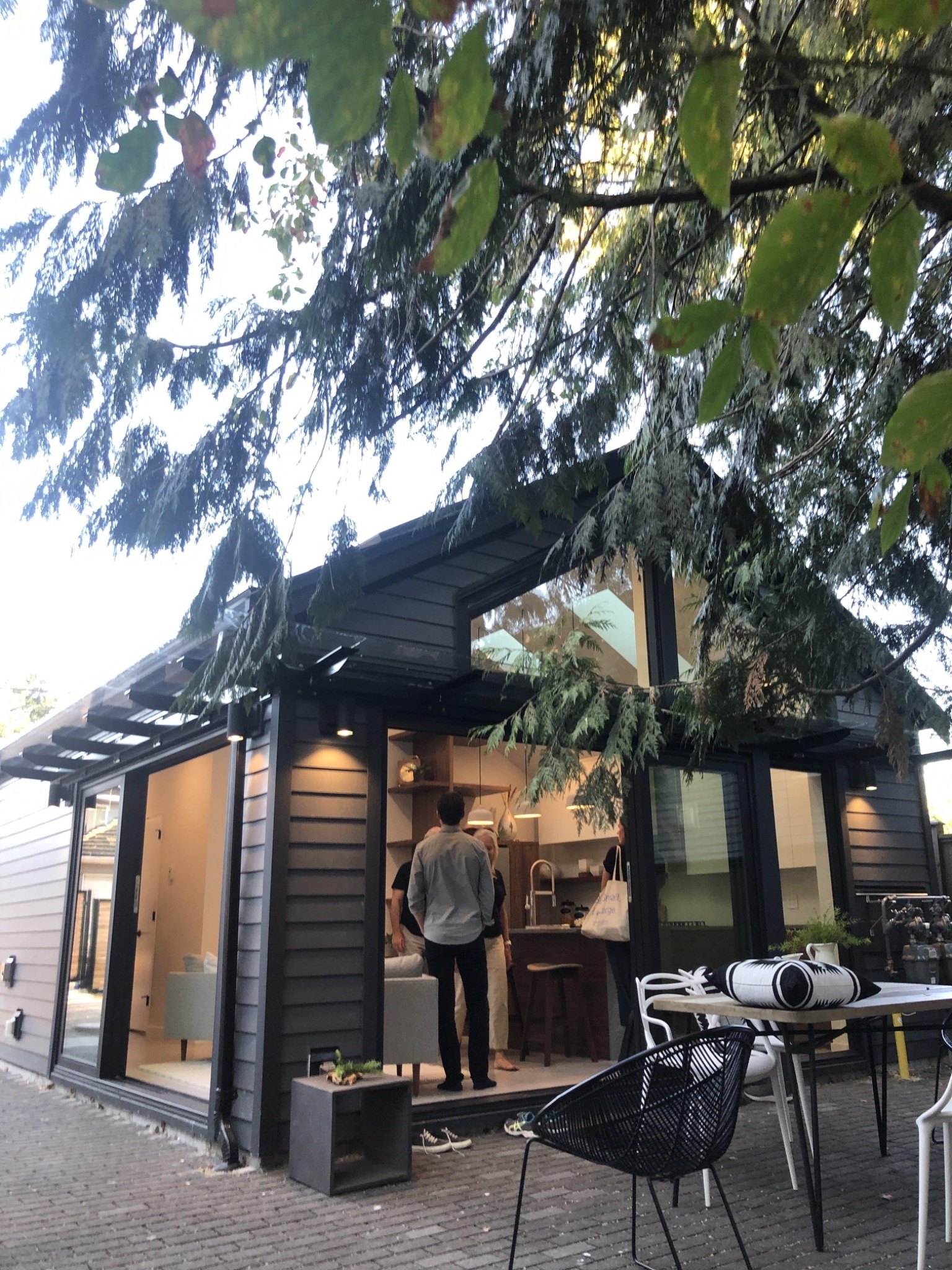 Built compact laneway home with dark exterior siding and warm interior lighting.